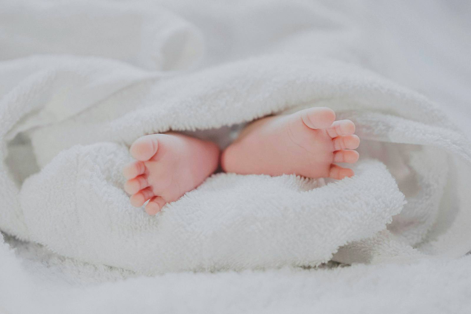 Mains de nouveau-né enveloppées dans un tissu doux, symbolisant la délicatesse de l'accompagnement.
